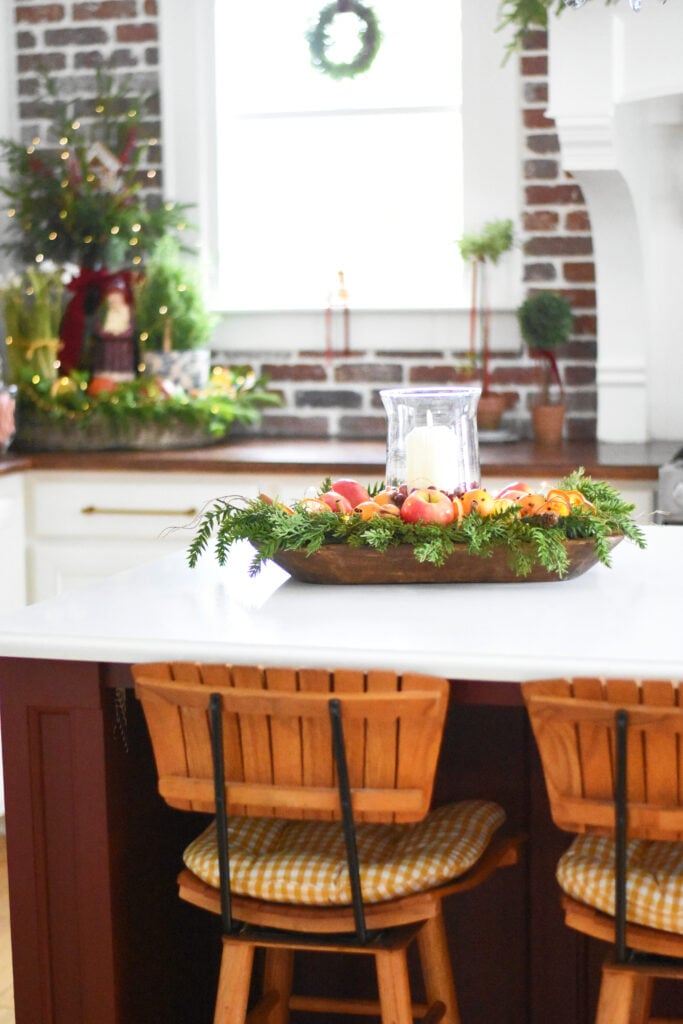 Christmas dough bowl with fresh fruit, orange slices, cinnamon sticks, nuts and cloved oranges orange pomanders. Candle centerpiece with cranberries