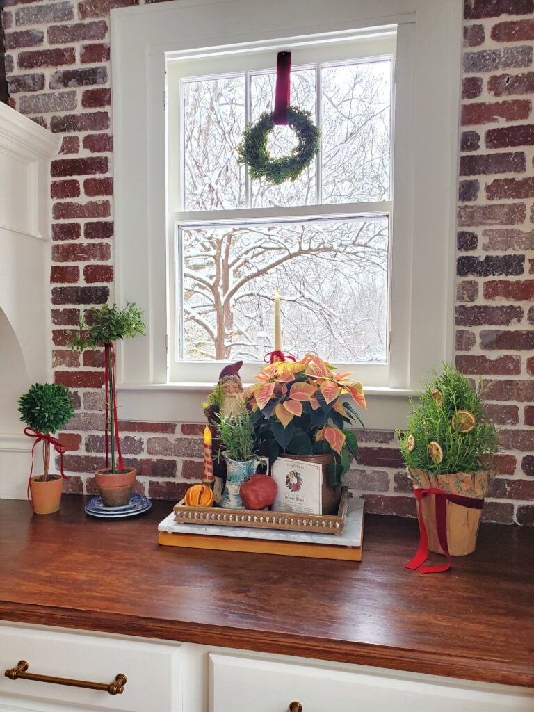 Christmas vignette with Belsnickel Santa, poinsettia and rosemary tree. Christmas kitchen with brick wall #Christmaskitchen